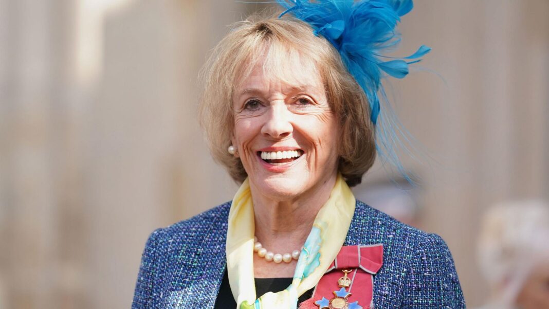 Esther Rantzen, pictured in 2022, wears a blue fascinator, blue blazer, yellow scarf and her CBE.