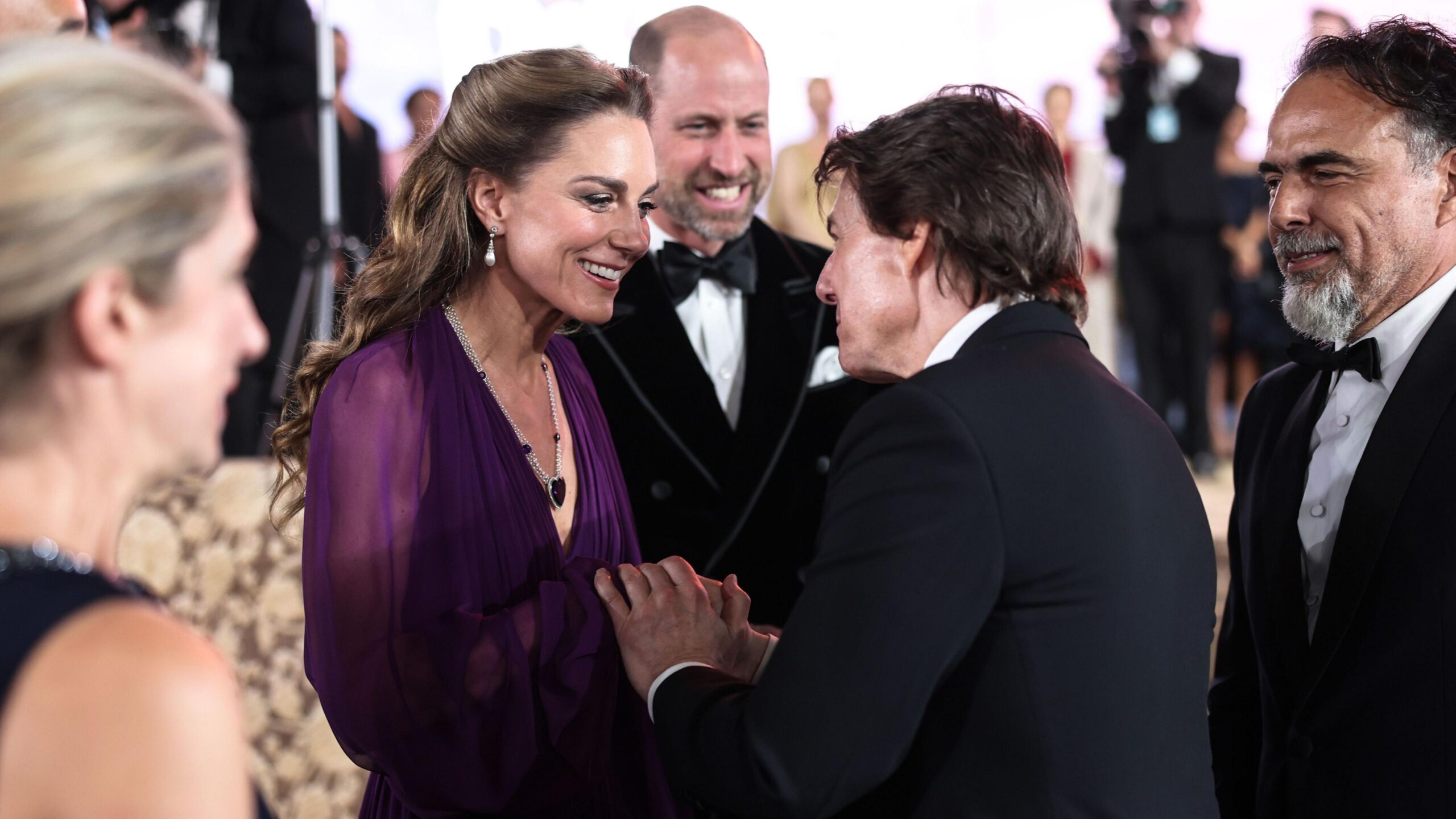 The Princess of Wales speaking to Tom Cruise, each clasping each other's hands, with the Prince of Wales behind them