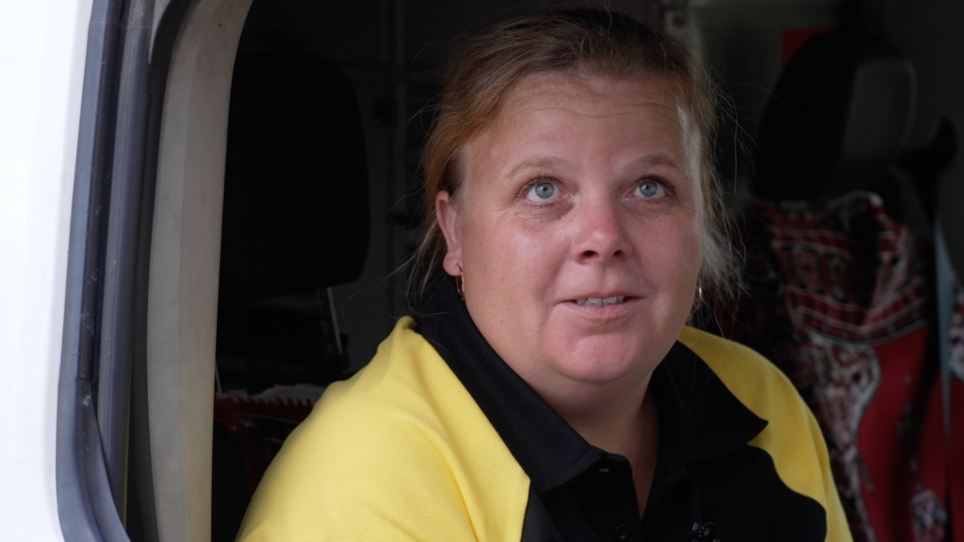 Kateryna Marynych sits in her yellow and black shirt in the front seat of her postal van in Zaporizhzhia oblast