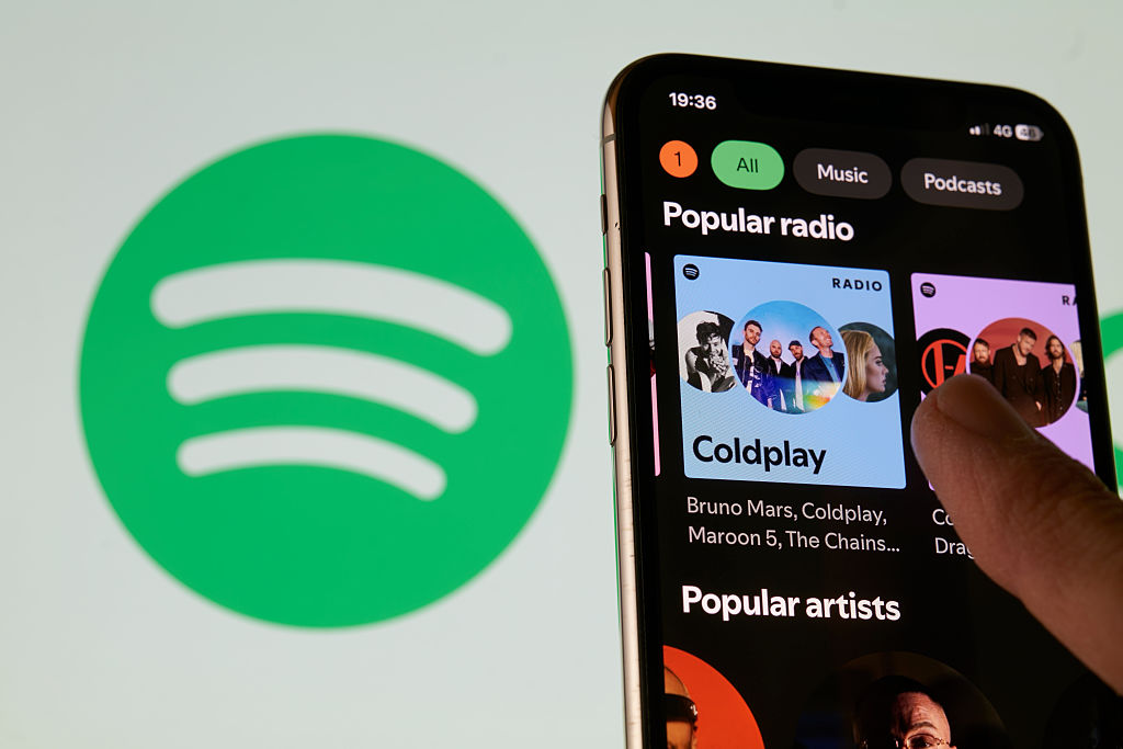 Close-up images show the Spotify logo and mobile application interface on a smartphone screen