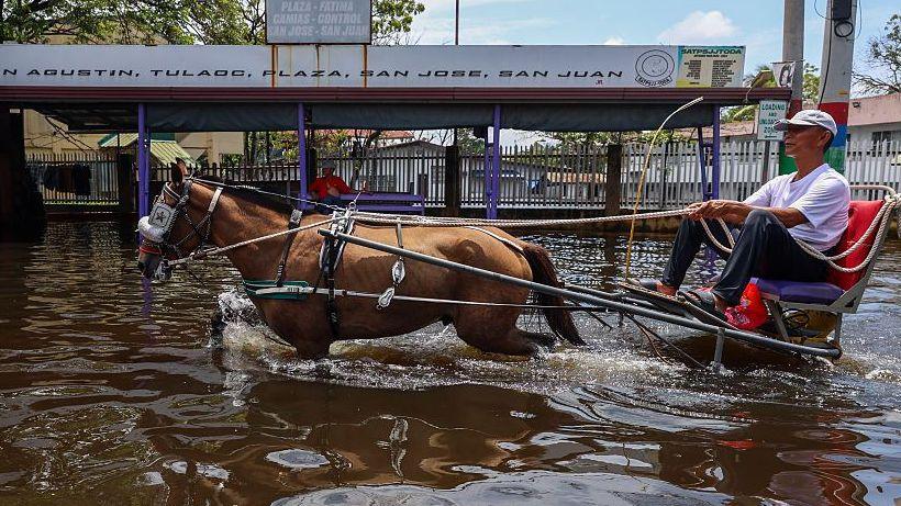 A man drives a horse and cart through high flood waters in Manila in the Philippines in August, where El Niño is expected to have a major influence on storms