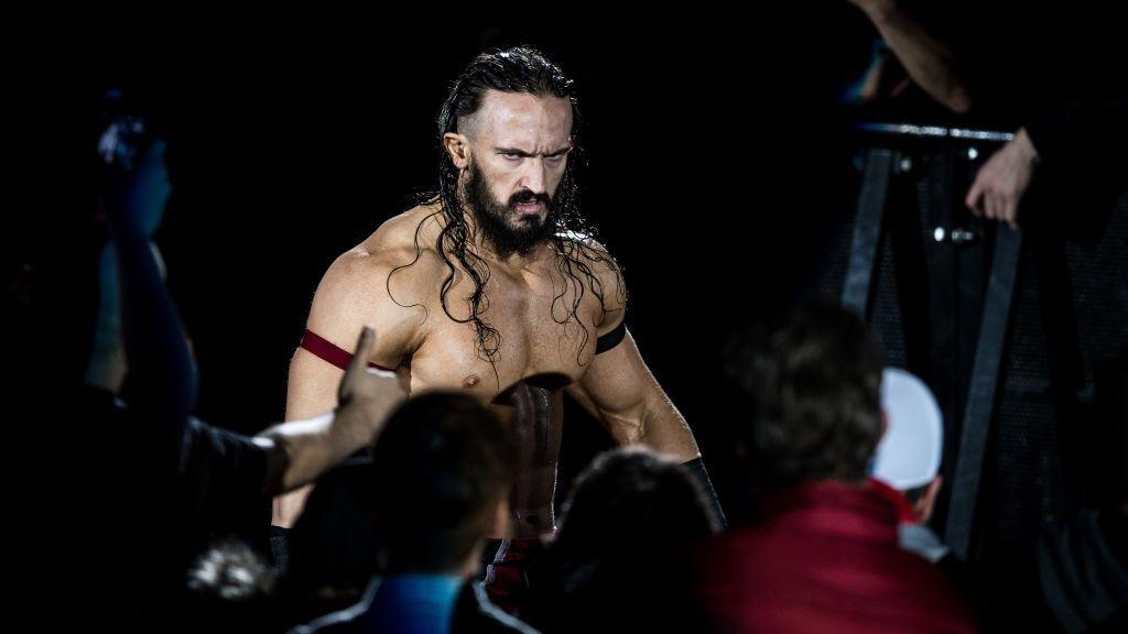 Wrestler Benjamin Satterley arrives at the 2017 WWE Live Duesseldorf. He is shirtless, has long brown hair, a beard and is glowering at the crowd.