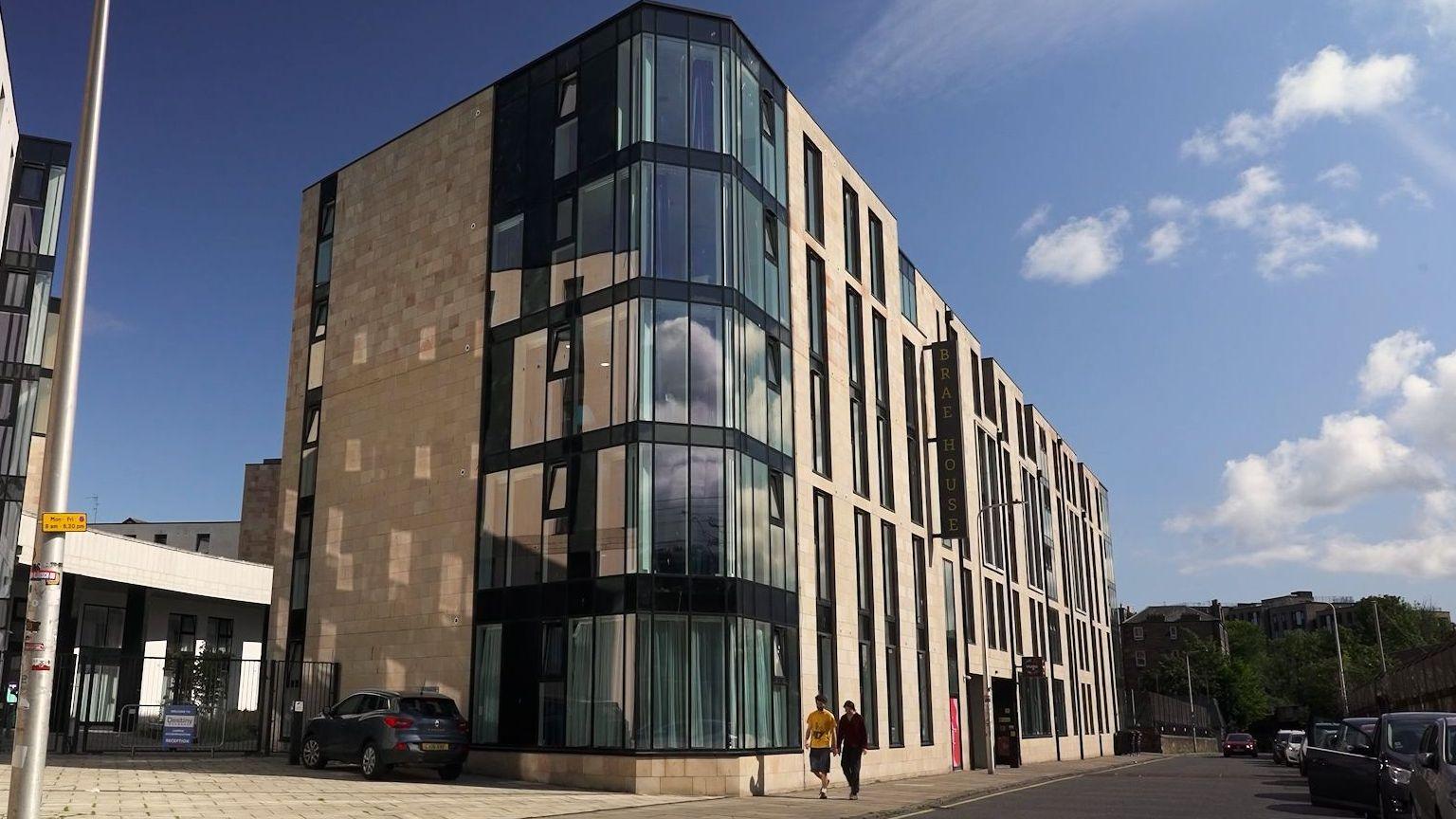 A five-story student accommodation block. It has beige walls and large windows.
