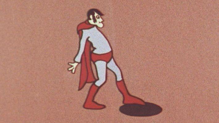 The original 'Aard Man' superhero 'dolt' that  Peter Lord and Dave Sproxton created in 1972. He is wearing blue and red superhero clothes but has a sticking out belly and a strange facial expression. He looks like he is about to fall into a hole.