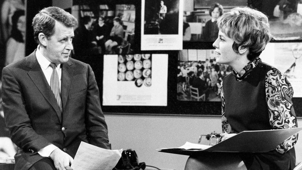 Bernard Braden & Esther Rantzen in Braden's week. This is a black and white photo showing a young Esther Rantzen interviewing Braden on set.