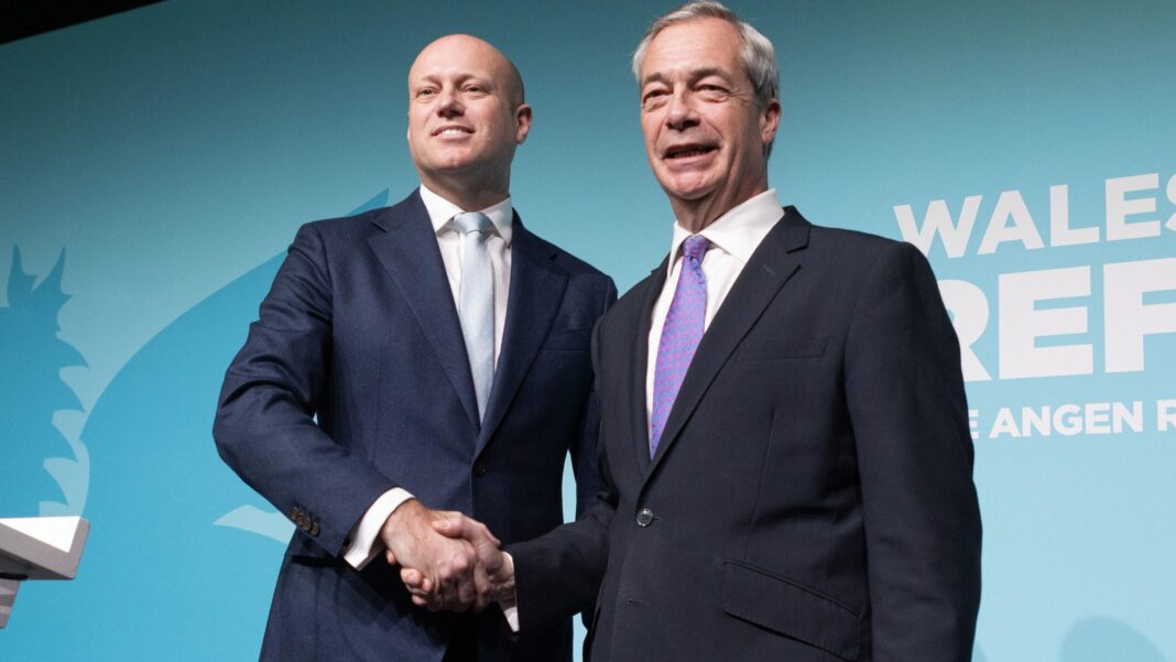 Dan Thomas shaking hands with Nigel Farage in front of a Wales Needs Reform banner.