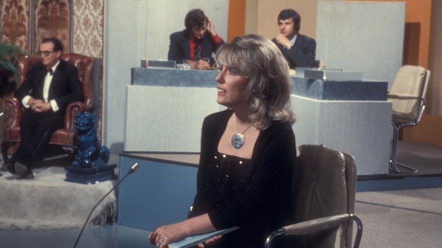 Esther Rantzen on the set of That's Life!  The photo shows her speaking to camera with her co-stars waiting to go on air behind her.