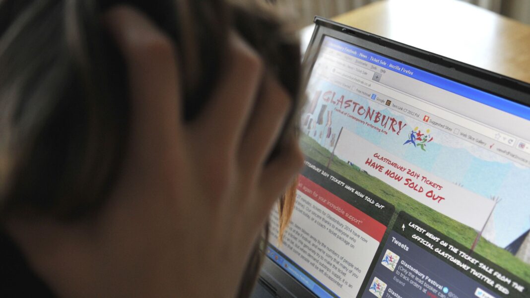 Mistakes to avoid when buying Glastonbury tickets A person looking at a screen that says Glastonbury Festival tickets have sold out