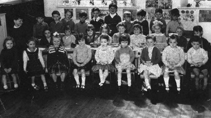A black and white image of children lined up for a school photo.