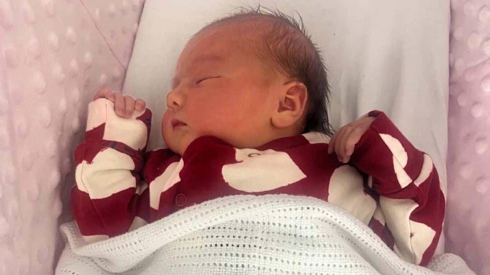 A baby in a red baby grow