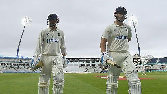 Warwickshire skipper Ed Barnard (left) and Sam Hain exit the field of play following a stoppage for bad light at an overcast Edgbaston