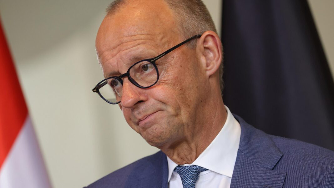 German Chancellor Friedrich Merz appears at a news conference wearing a blue suit and tie, white shirt and glasses.