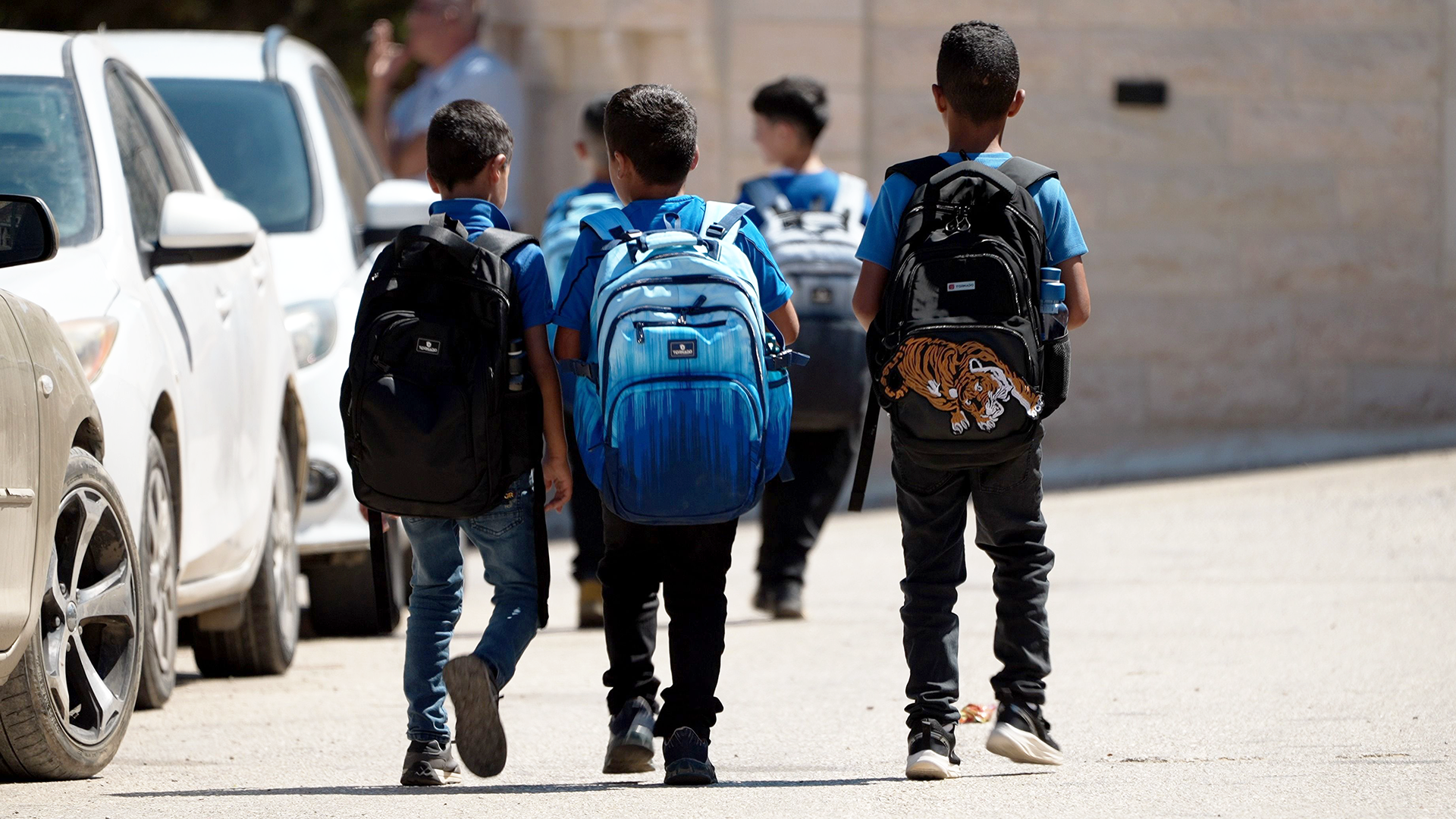 Palestinian kids walk to school. They are wearing blue school uniforms.