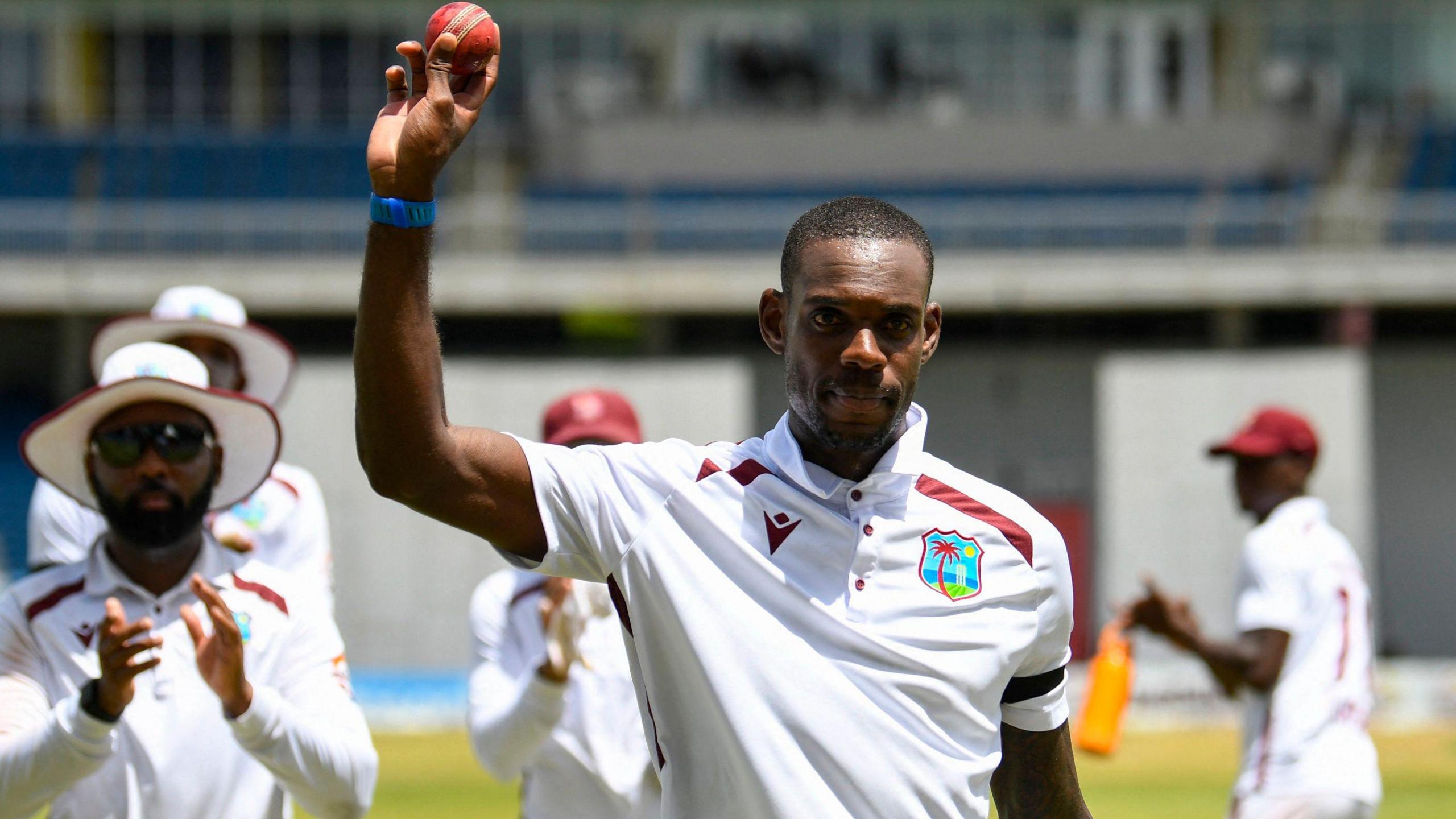 West Indies all-rounder Justin Greaves holds the ball aloft as he is clapped off the field by his team-mates in Trinidad