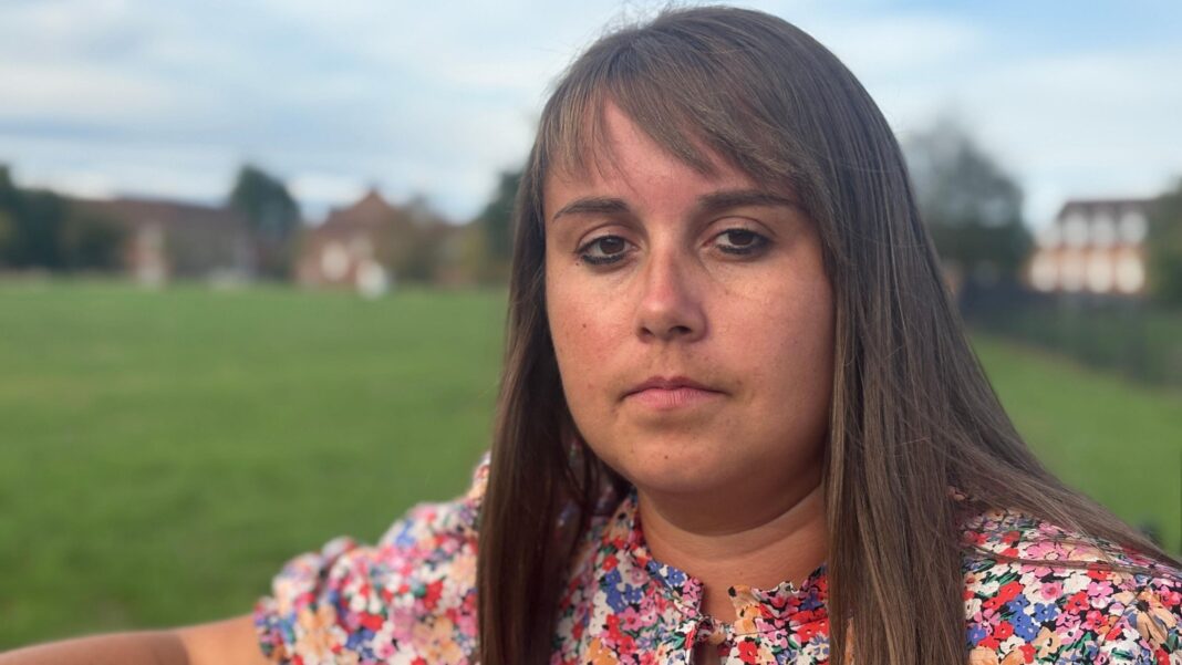 I had 11 years of chemotherapy for a cancer I didn’t have Becky Jones has shoulder-length brown hair with a fringe. She is standing in a park and is wearing a dress with multi-coloured flowers on it.