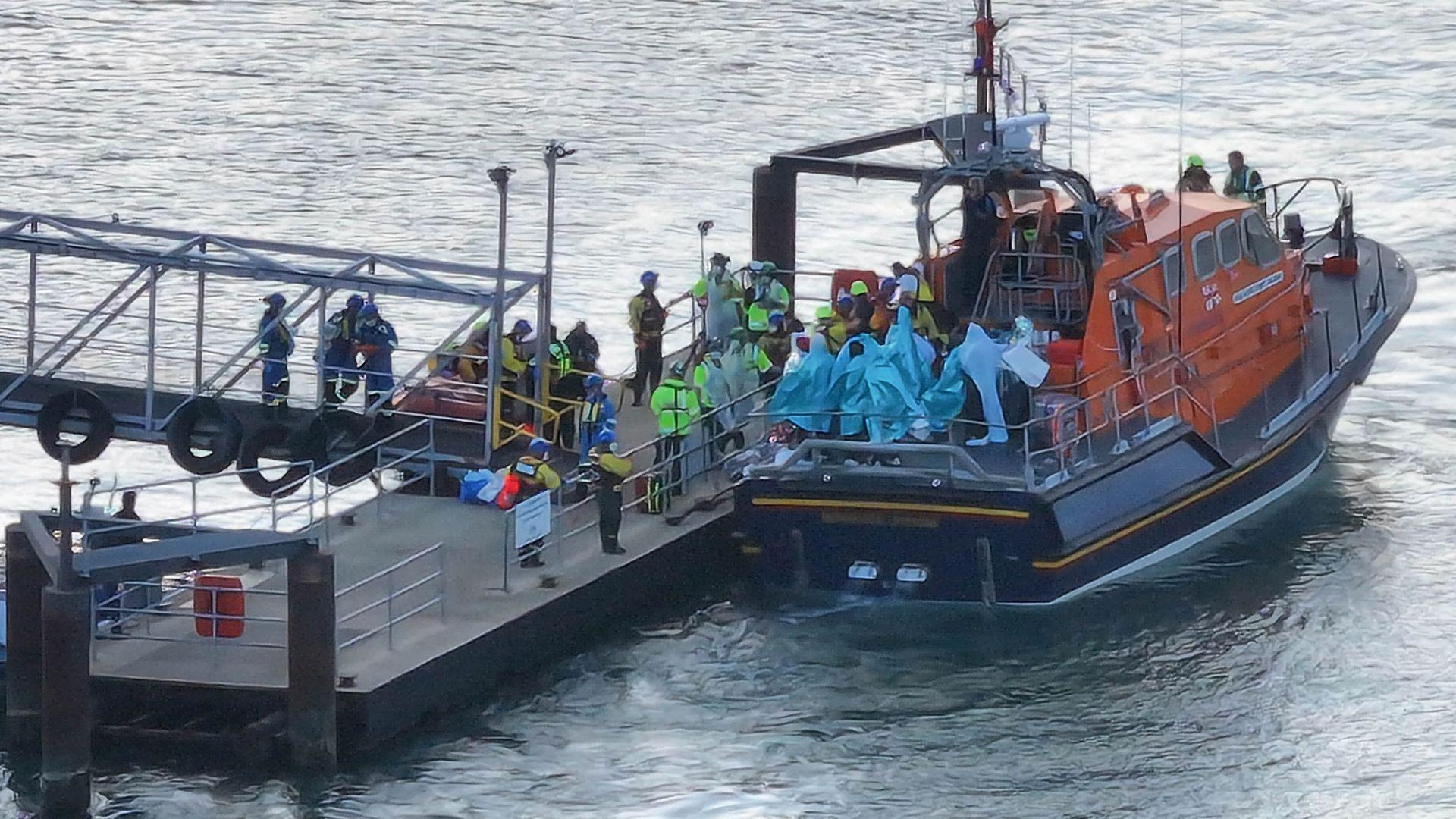 People wrapped in blankets on the back of an RNLI lifeboat moored by a pontoon at Eastney, Portsmouth, on 6.9.26