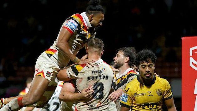 Bradford players, in white strip, surround try-scorer Ebon Scurr as Castleford Tigers' Phoenix Laulu-Togagae walks away dejectedly.