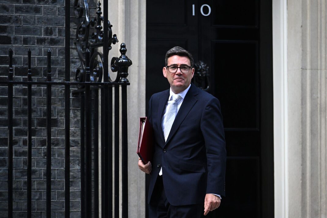 Andy Burnham stands in front of the door to No 10 in a suit and tie holding a binder on 1 September.