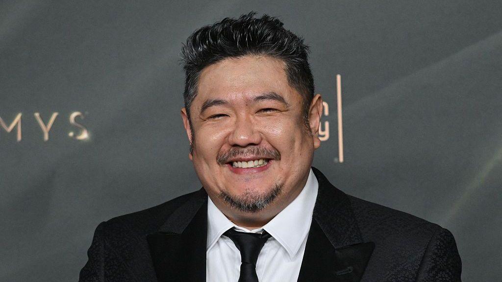 A man in a dark suit with a close-cropped goatee smiles at a premiere