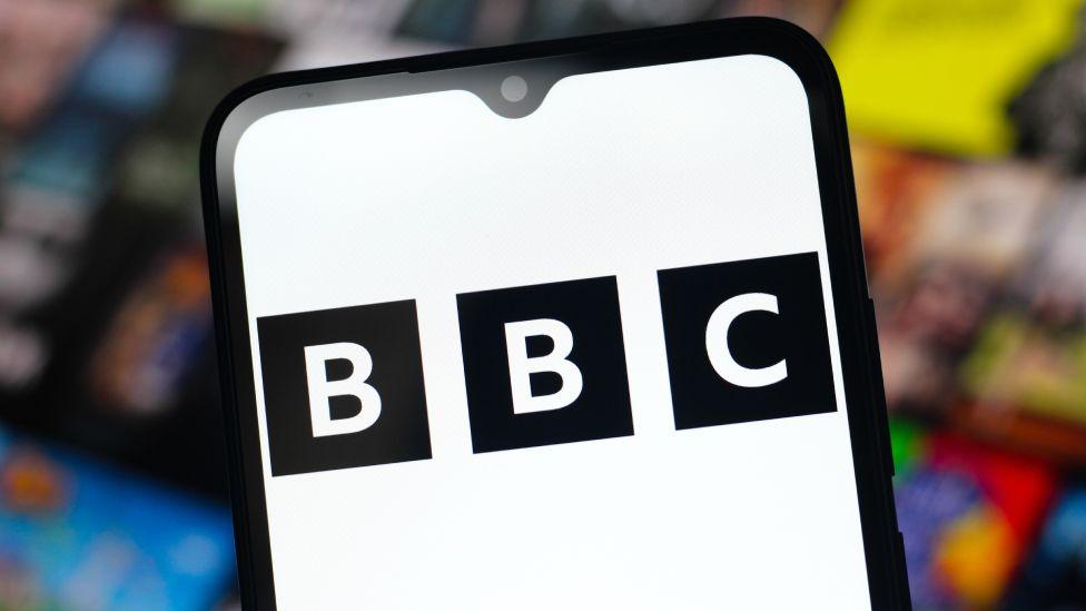 The BBC logo is seen displayed on a smartphone screen
