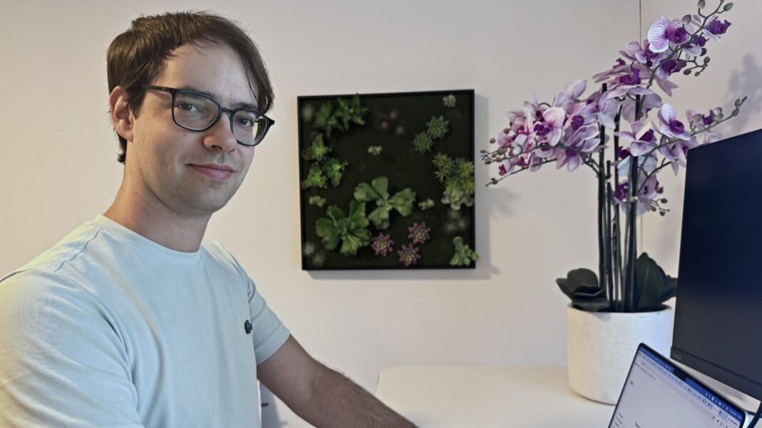 John Zimmerman wears glasses and white t-shirt and sits at his laptop