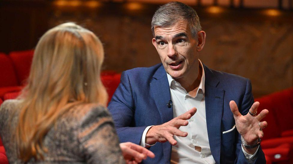 Matt Brittin wearing a blue blazer speaking to Laura Kuenssberg