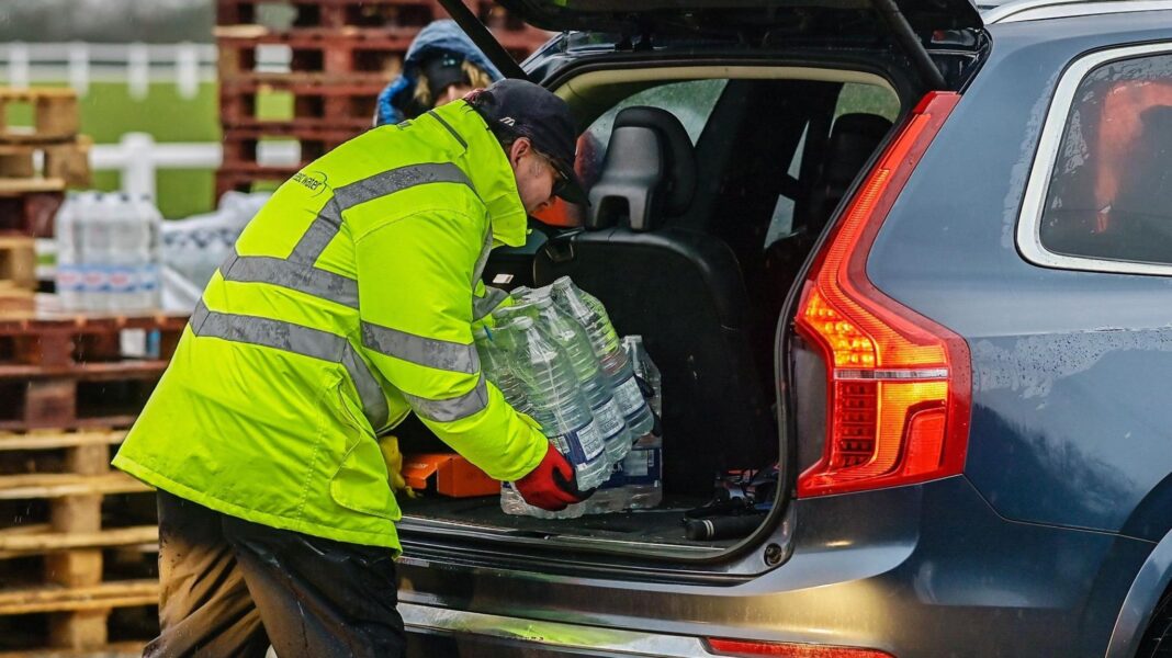 Serious pollution by water industry remains high despite £5bn investment A man in a high-vis jacket, black trousers and a cap, wearing red gloves loads bottles of water into the boot of a blue SUV. In the background are pallets with more bottled water.