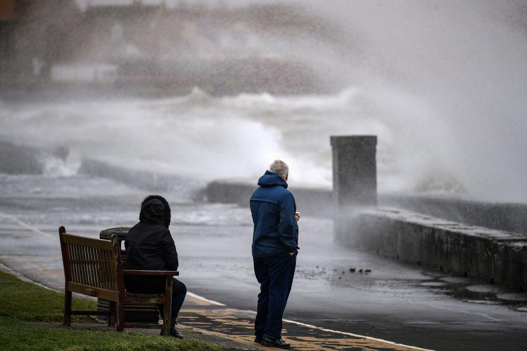 Two people looking out to a very rough sea