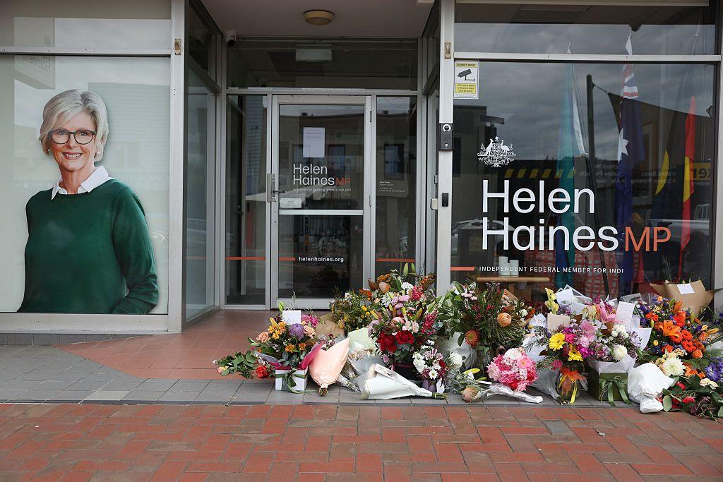 An office window with piles of flowers outside and a decal of a smiling middle- aged woman