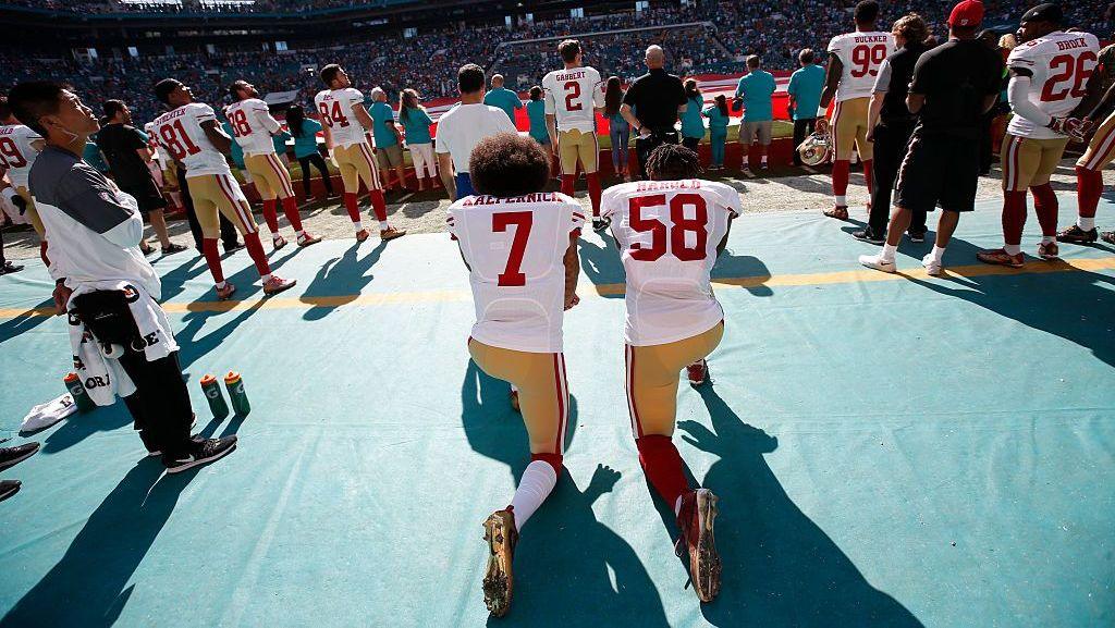 Colin Kaepernick kneels before a match