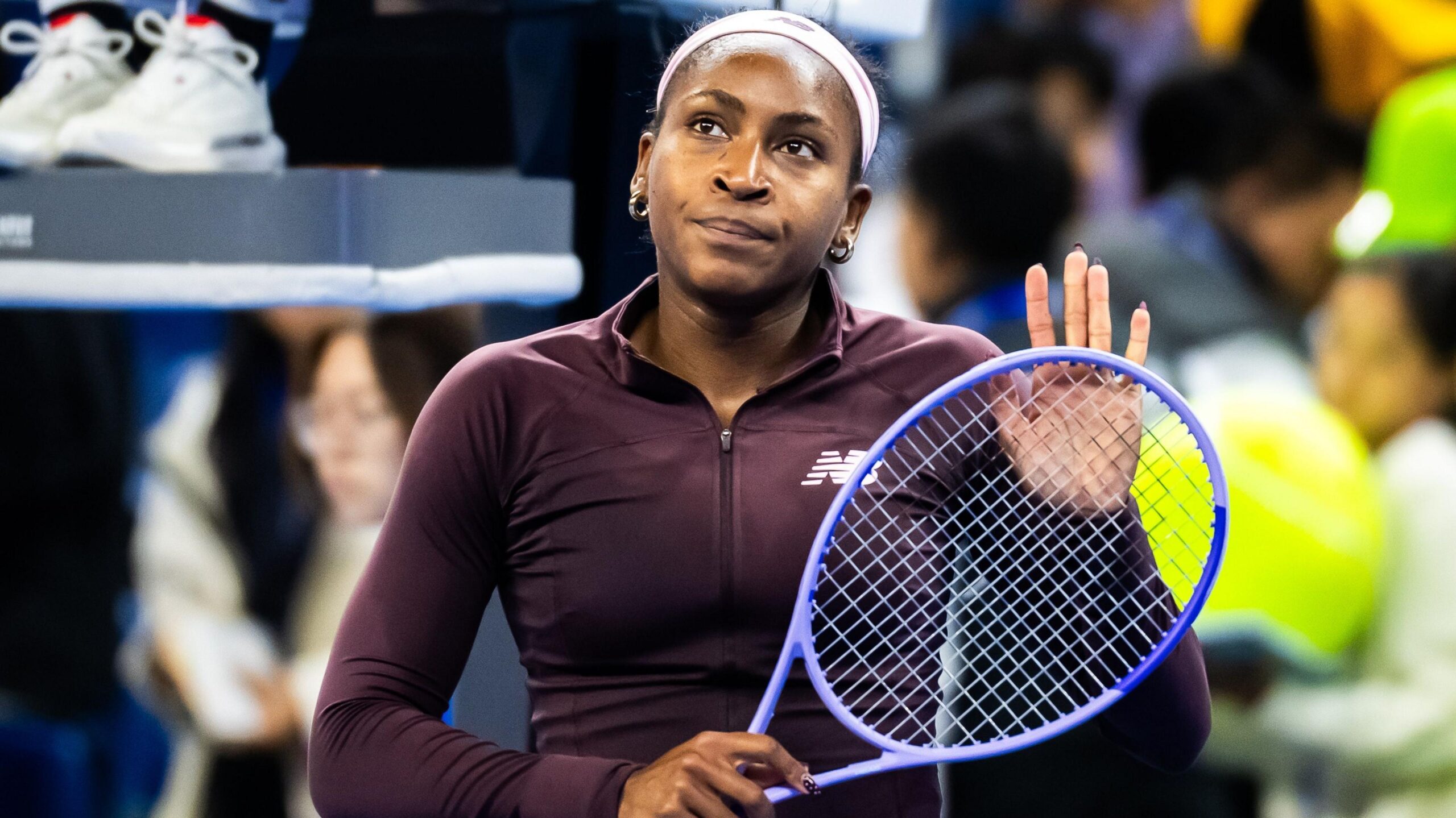 Coco Gauff pats her racket against her hand with a forlorn expression