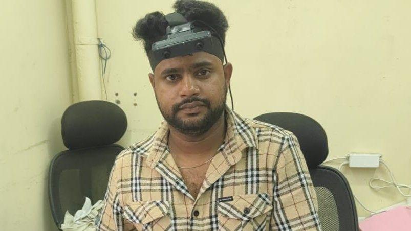 Mohammed Arman has a black headband with a camera attached. He is wearing a beige checked shirt.