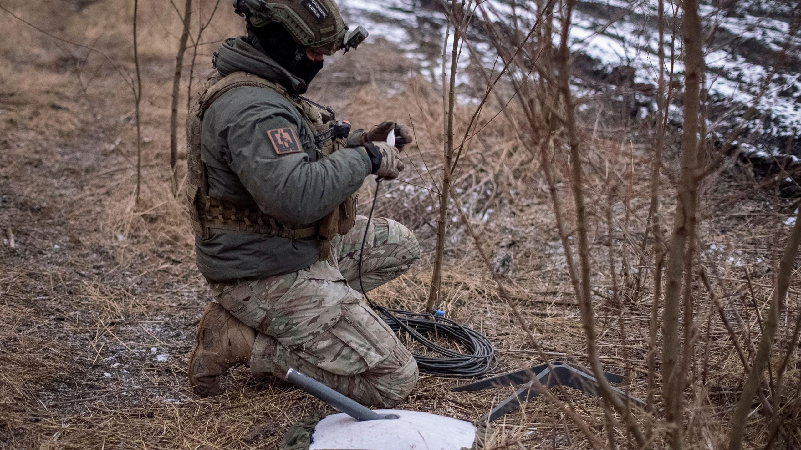 A Ukrainian serviceman of 47th brigade prepares a Starlink satellite internet systems at his positions at a front line, in February 2024
