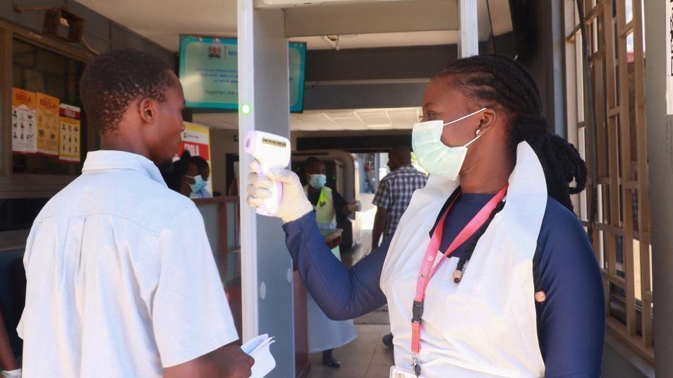 A female medical worker checks the temperature of a male traveller with a scanner at the Malaba crossing-point between Kenya and Uganda on 8 October