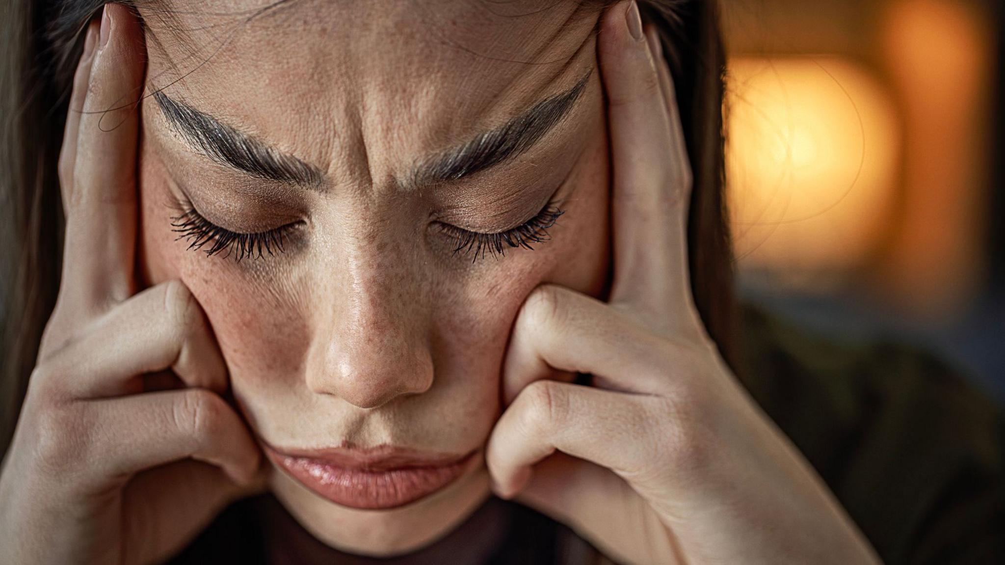 A woman looking stressed out wit her fingers pressed against her temples