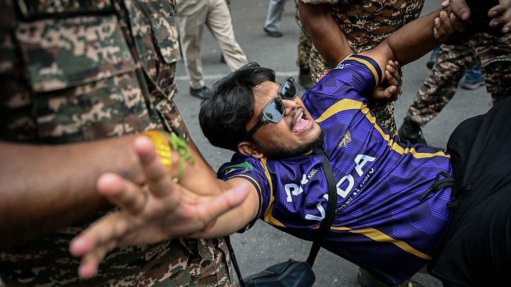 Security personnel detain a demonstrator during a protest demanding the resignation of India's Chief Election Commissioner Gyanesh Kumar over alleged voter roll irregularities linked to the "special intensive revision" (SIR), near Jantar Mantar in New Delhi on October 11, 2026.