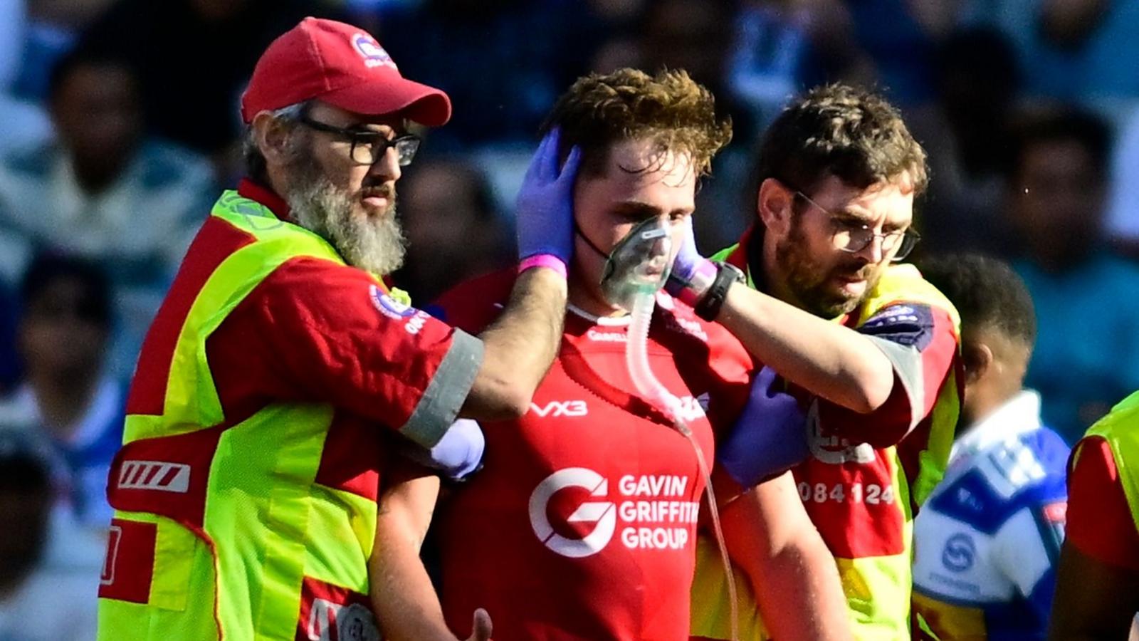 Scarlets Macs Page wing is helped from the field while being given oxygen
