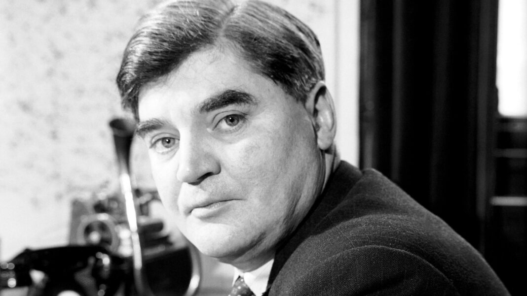 A black and white head and shoulders photo of Nye. He has short hair, with a side parting, and wears a suit, shirt and tie. He is looking at the camera with a serious expression.