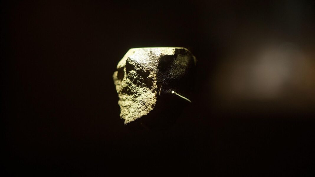 Mission blasts off for Mars to grab a piece of its moon A close up image of a Martian meteorite which is on display at the Natural History Museum. It is small and irregularly shaped, it is lit from one side showing its rough texture. It is against a black backdrop of the display cabinet.