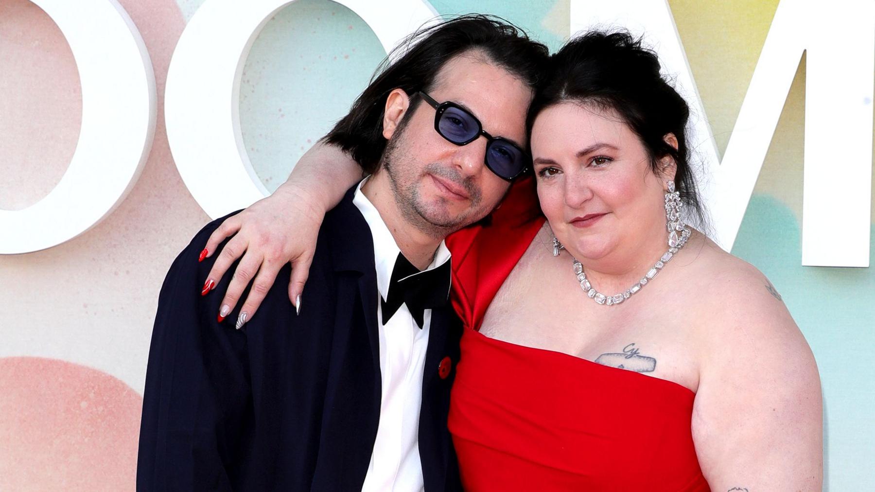 Luis Felbar and Lena Dunham look at the camera while embracing and posing in front of a colourful background on the red carpet of a screening of Too Much at the Barbican in London in 2025.