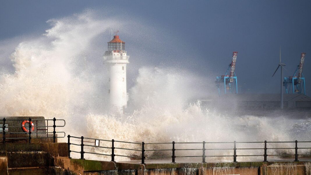 Waves crash over the lighthouse in New Brighton against a dark sky on Sunday.