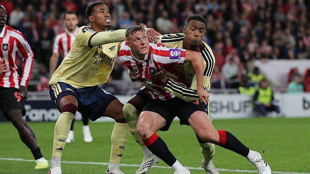 Arsenal's Ezri Konsa has two arms around the waist of Dan Ballard of Sunderland leading to a penalty kick