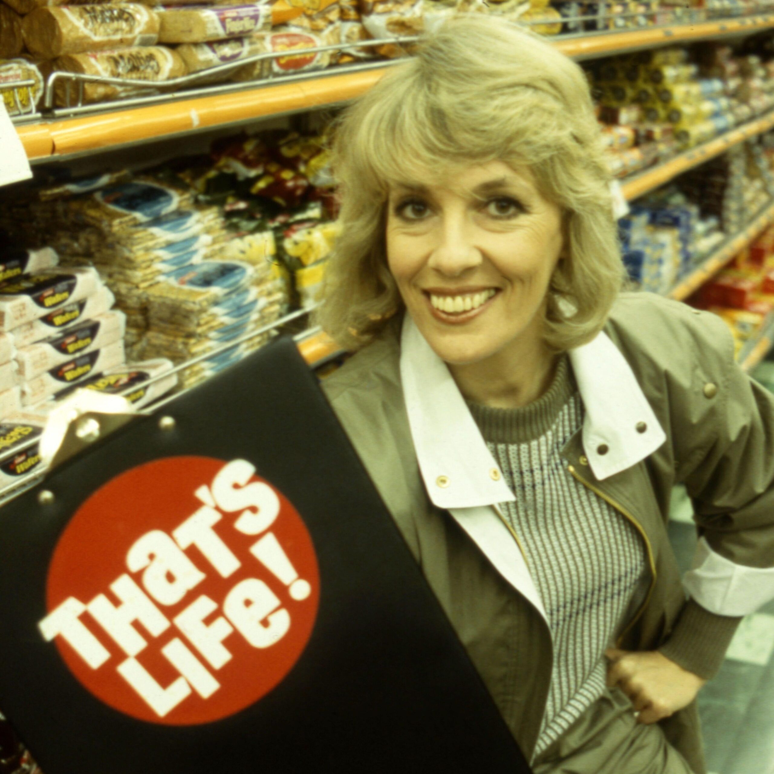 Dame Esther Rantzen in a supermarket in 1983 holding a clipboard with the That's Life! logo