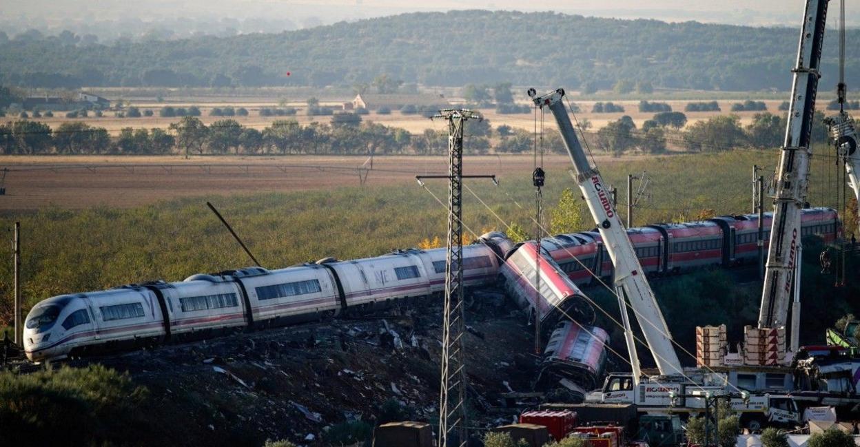 View of the two smashed trains near Toledo, Spain, 29 Oct 2026, with rescuers' cranes at scene and a plain and hills in background