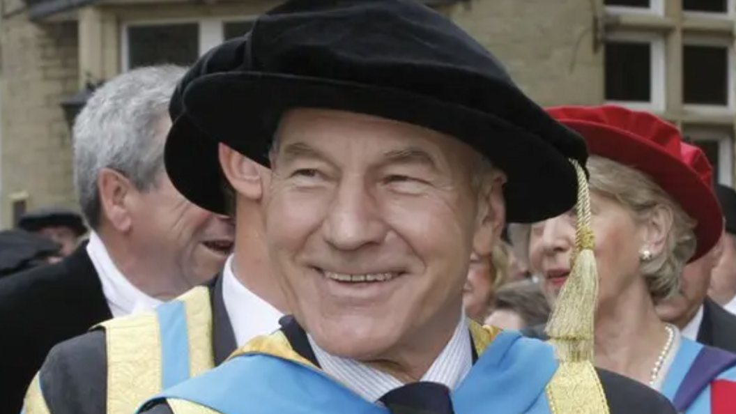 A smiling man wearing a suit and academic dress.
