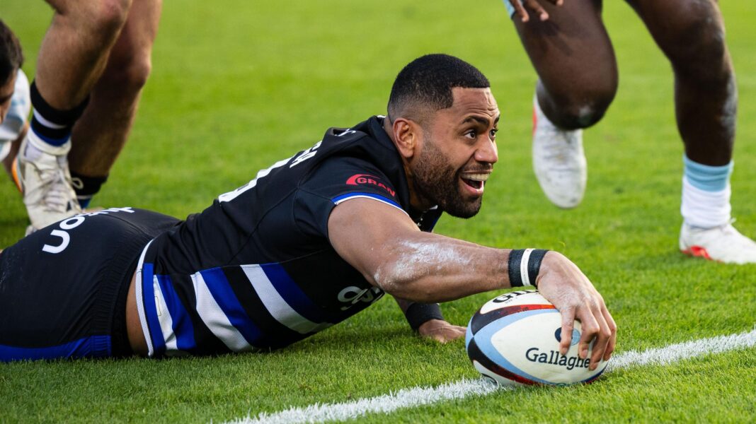 Joe Cokanasiga lies down and holds the ball over the line with one hand as he scores a try