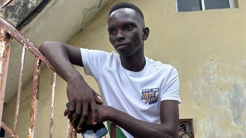 A young man in a white T-shirt leading on the rusty hand rail of a flights of stairs