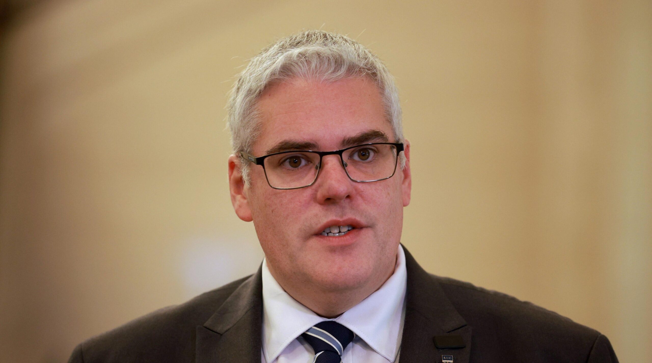 DUP leader Gavin Robinson is a man with grey hair and wearing glasses dressed in a dark suit with shirt and tie