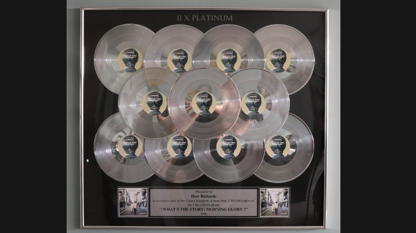 11 silver CDs mounted in a black frame with a plaque beneath