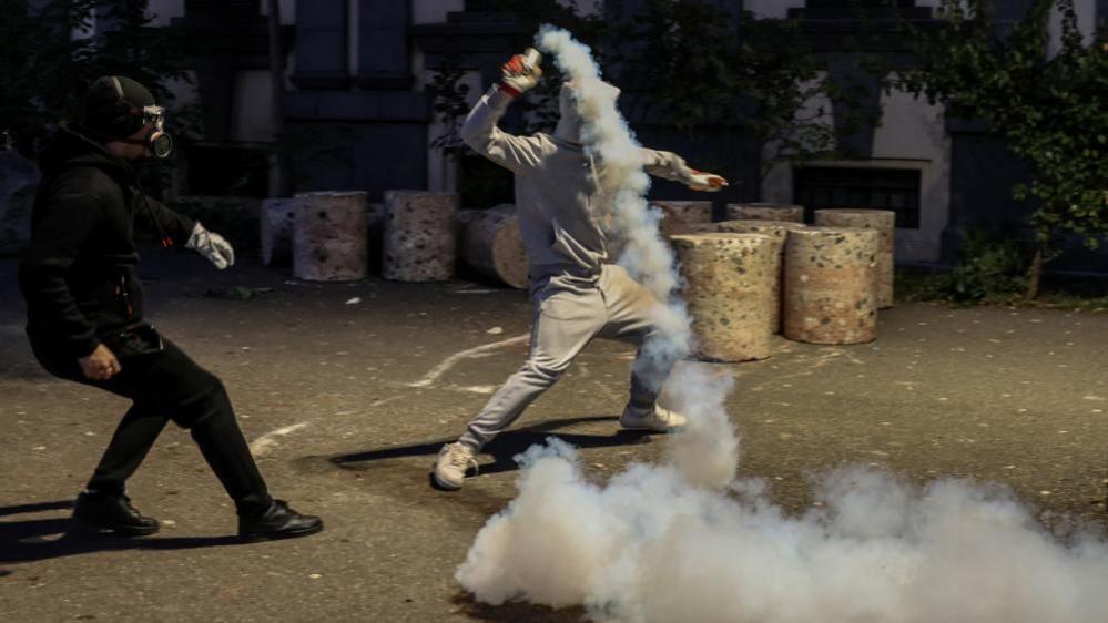 A protester throws a tear gas garnster back towards police, during an anti-government protest by students in Tirana, Albania, October 19.
